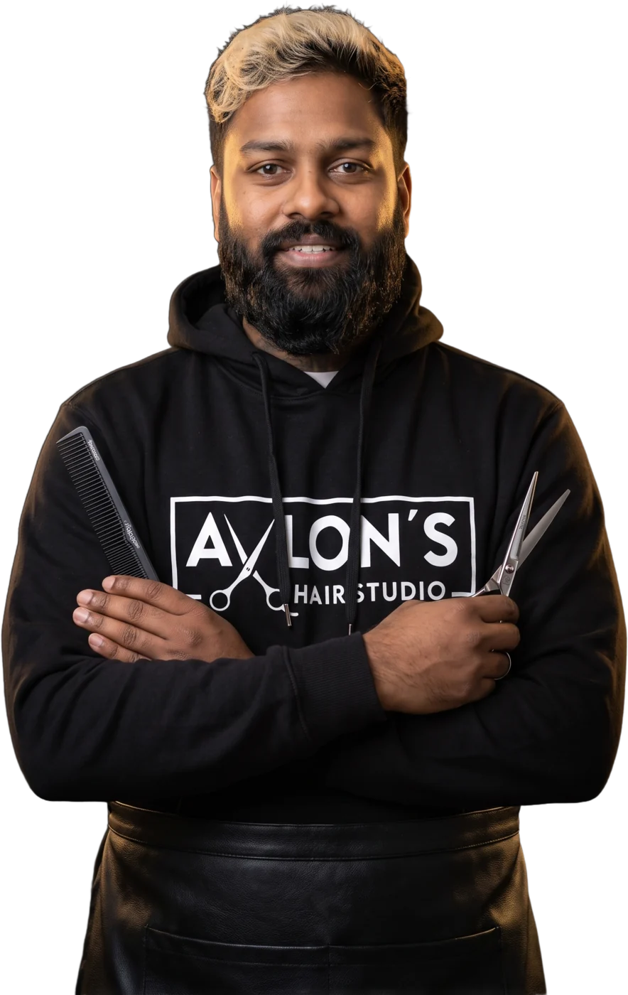 Reagan Fernandes, owner of Avlon's Hair Studio, arms folded holding scissors and a comb